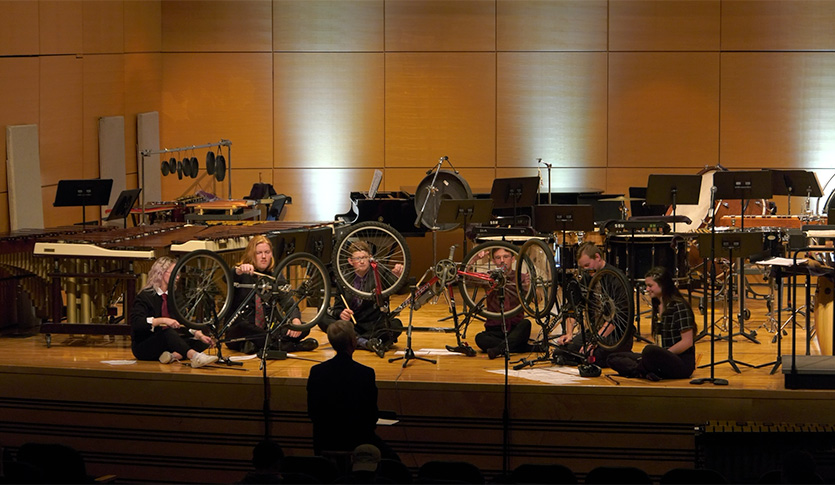 Percussionists playing bicycles at a concert.