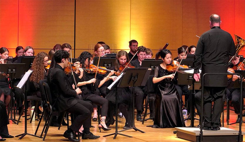 A picture of the Central Michigan University Symphony Orchestra in black attire performing at Staples Family Concert Hall.