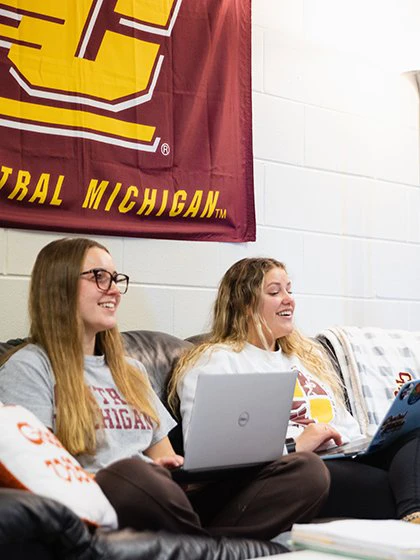 Students in dorm room with laptops working on social media