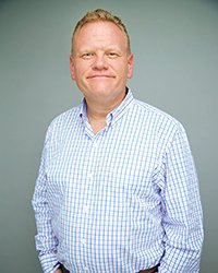 Headshot of Larry Joe Campbell on a soft teal backdrop.