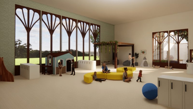 3D view of autistic center playroom with children and adults playing in a large white room with large windows and various plat structures around the room such as a blue playhouse, blue ball, and yellow cushions.