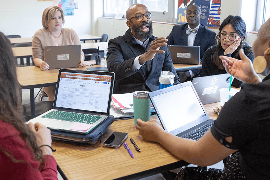 group of adults in a discussion with laptops