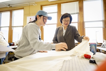 A professor and student in the fashion lab handling fabric.