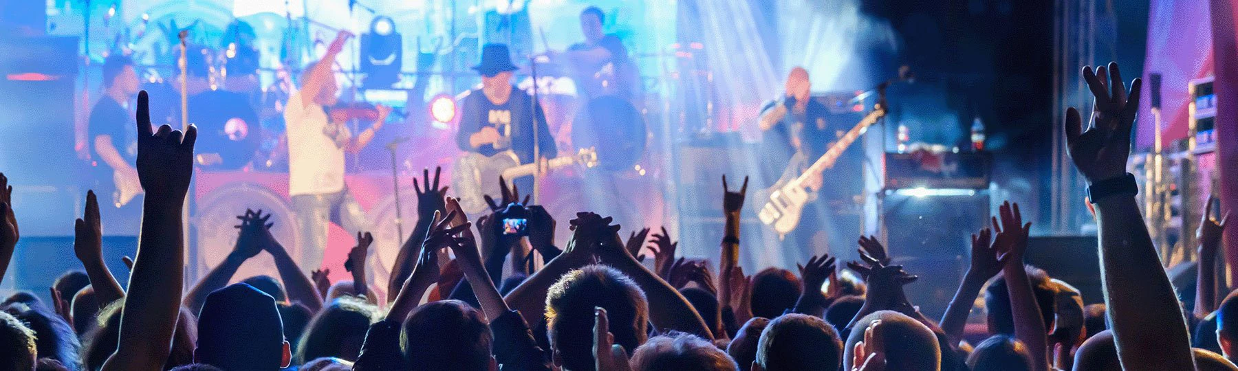 A band giving a concert. Fans are waving their hands in the air.