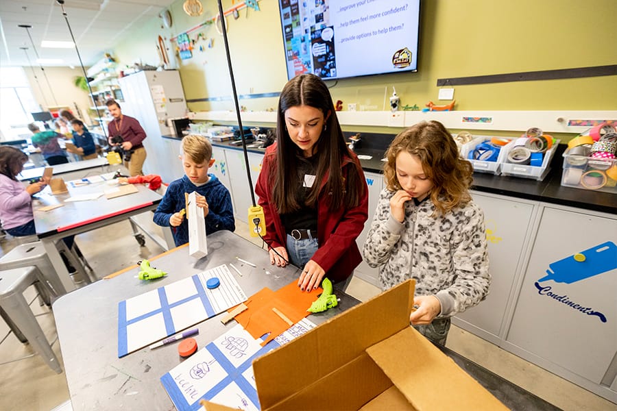 An integrated science student teacher candidate works with to young students in the Center for Excellence in STEM Education.