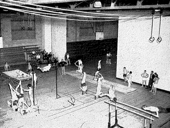 A historic black and white photo of men's gymnastics inside Finch Fieldhouse.