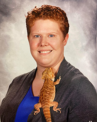 Image of Liz Davidson smiling with a lizard clinging to her sweater.