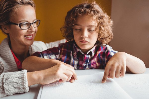 Adult and child read page from a Braille book together