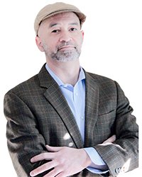 Adrian Hemond standing with his arms crossed while wearing a hat and suit jacket.