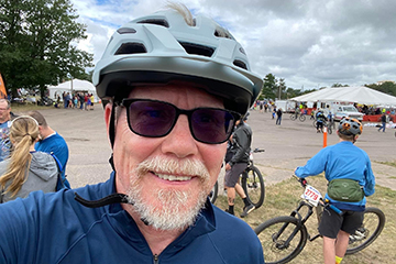 Larry Sych wearing a bike helmet and sunglasses at the Ore to Shore Mountain Bike Epic.