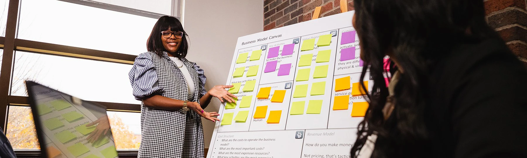 A woman in business attire is presenting information in a conference room.