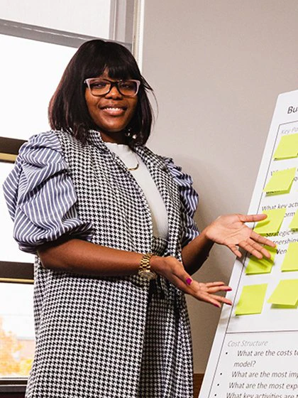 A woman in business attire is presenting information in a conference room.