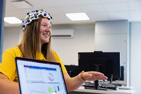 A student sitting in a chair wearing a hat made of sensors.