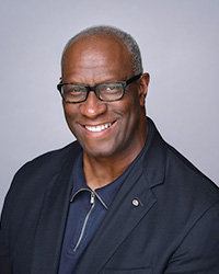 Robert Magee in a blue shirt and jacket smiling at the camera.