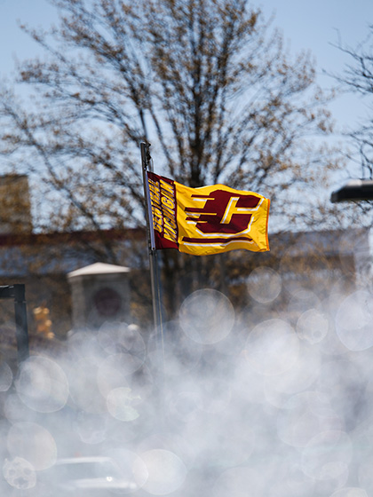 A gold flag with a maroon flying C waving from a flag pole.