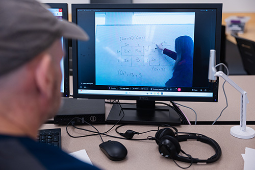 Student participating in an online math tutoring session, viewing a virtual whiteboard where an instructor is explaining algebraic equations.