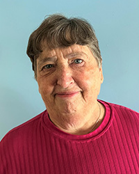 A woman with short brown hair in a red shirt smiles for a headshot image.