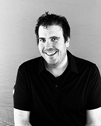 A black and white photo of a man in a black shirt.