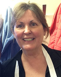 A woman with brown hair wearing a dark blouse and smiling at camera.