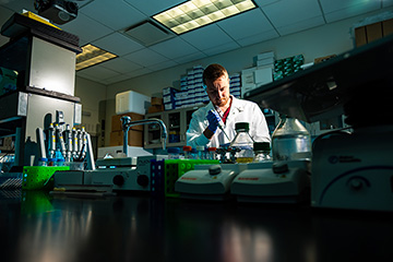 A man in a white lab coat working in a laboratory.