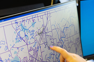 A finger pointing at environmental data on a map on a computer screen.A finger pointing at environmental data on a map on a computer screen.