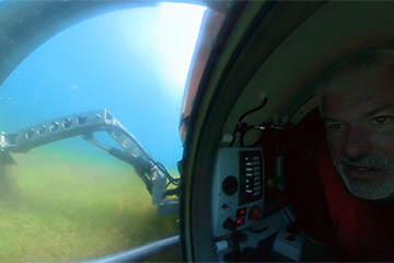 Don Uzarski inside a small submersible vehicle deploying a robotic arm.