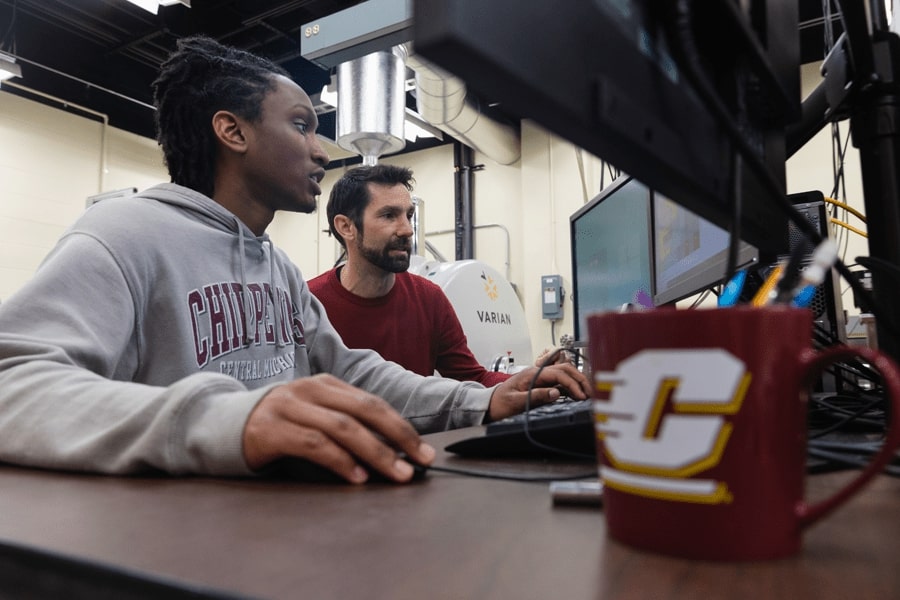 A physics student looking at a computer screen with Matthew Redshaw.