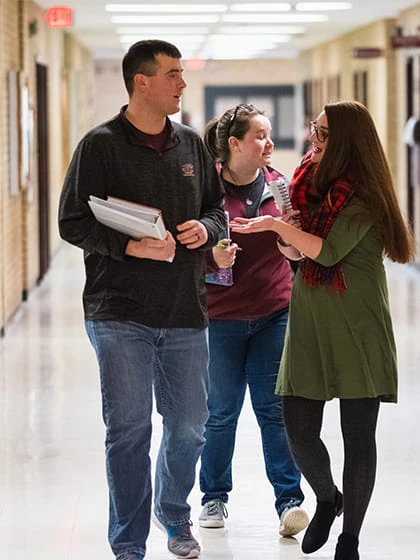 A group of mathematic students walk down the hallway on campus.