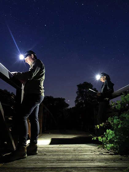 a man and woman with headlamps on a bridge