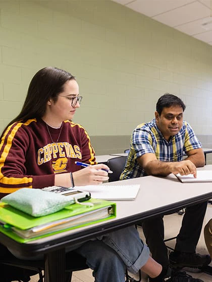 A female student in a Central Michigan University sweatshirt works with a faculty member in a button up.