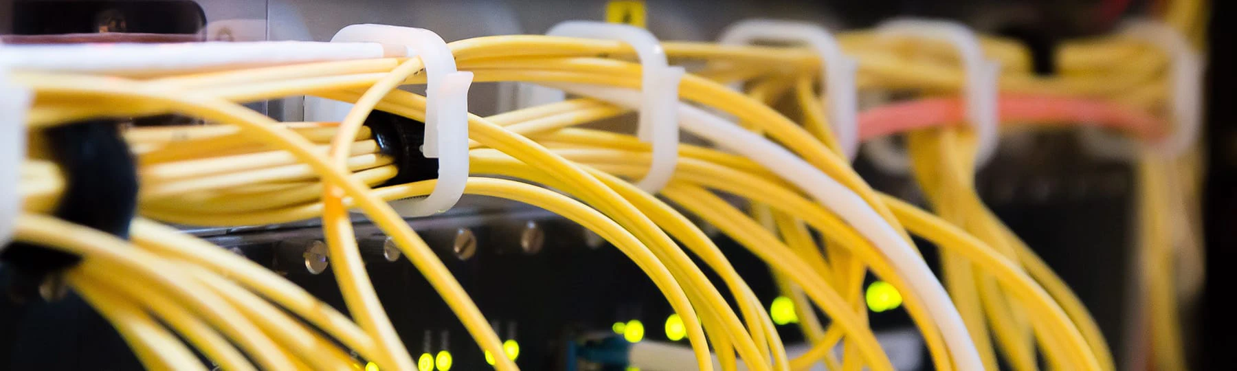 Yellow network cables running along a black machine with green lights on.