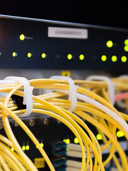 Yellow network cables running along a black machine with green lights on.