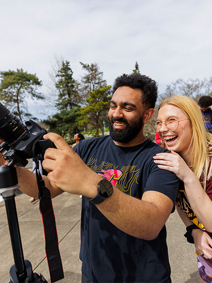 Two students looking at the solar eclipse through a camera