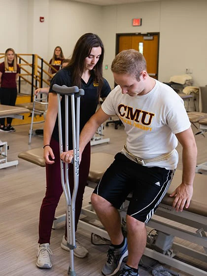 A pre-occupational therapy student works with a patient with crutches.