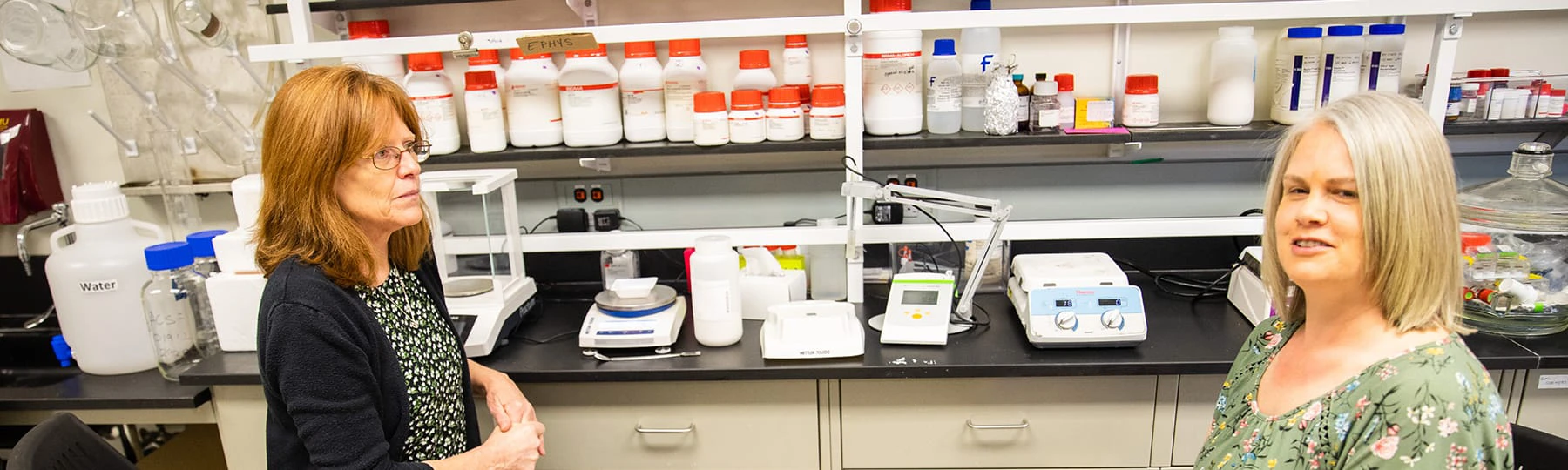 A pre-pharmacy student talks with a professor in an on-campus lab.