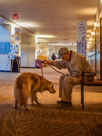 A golden retriever and a man in a baseball cap sit together at Central Michigan University.