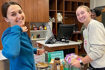 Two students pose together at a cooking station in the test kitchen on campus.