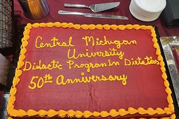 A Dietetics Program Anniversary cake with maroon and gold frosting.