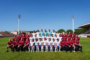 A soccer team posing together for a photo on the soccer field.