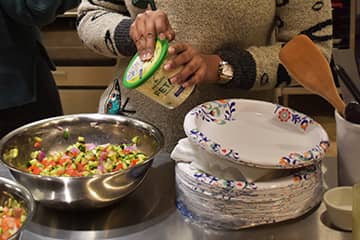 An individual adding food into a bowl.