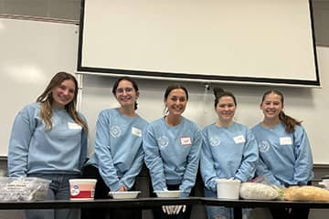 A group of students standing together wearing matching blue sweatshirts.