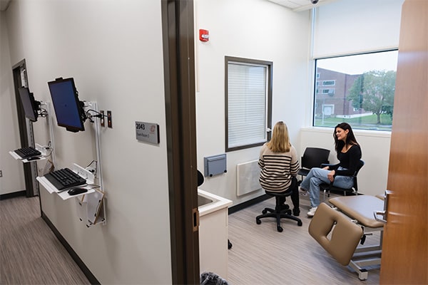 Two students sit together in chairs in an examination room in the IPEP Center.