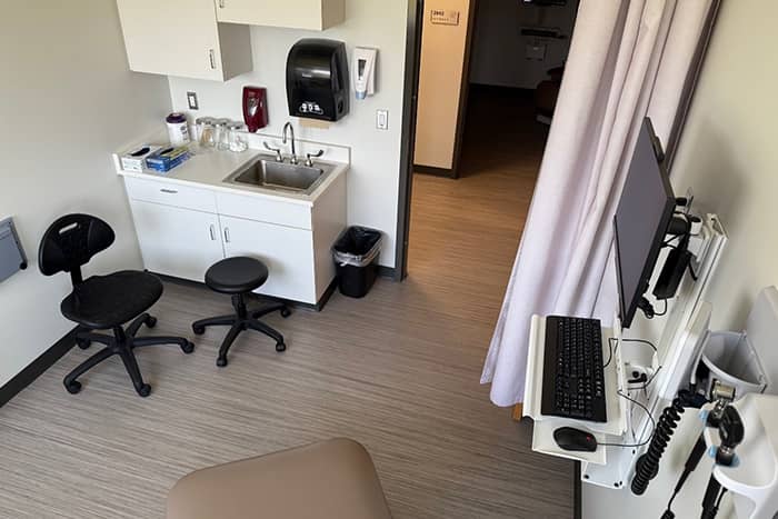 An examination room with a sink and a computer.