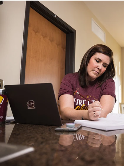 A nutrition and dietetics master's student works through online coursework at her kitchen island.