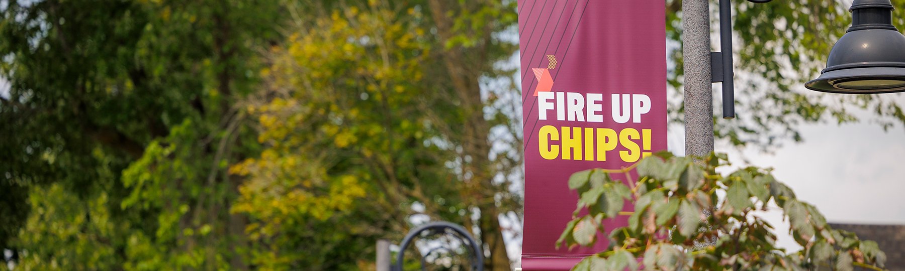 A Fire up, Chips! banner hangs from a light post on campus