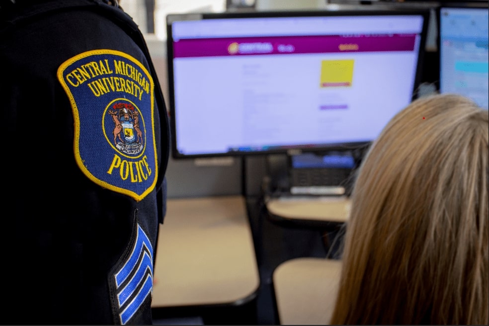 Dispatcher and Sergeant speaking about a case in the dispatcher center in low light with computers.