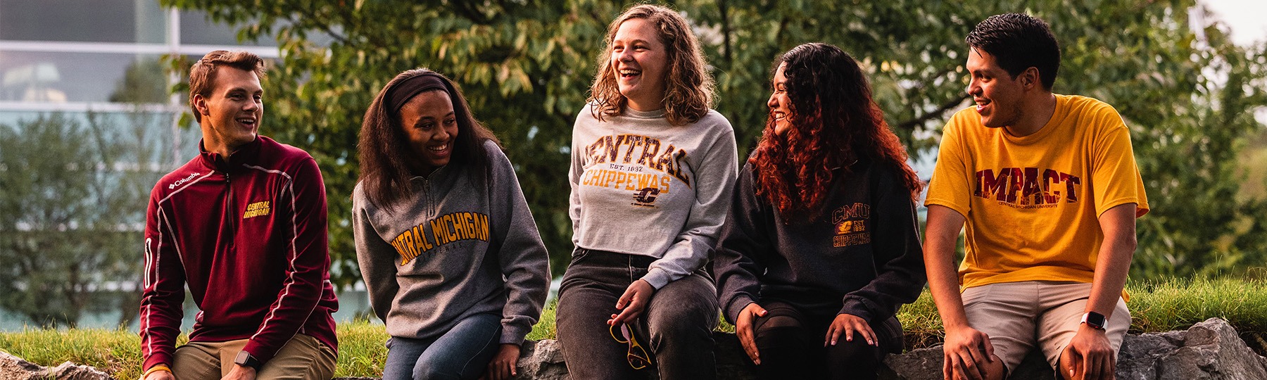 Students smiling and sitting in front of the library.