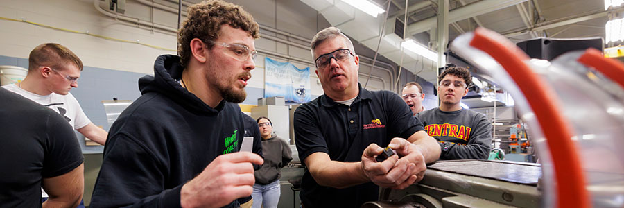 A group of men wearing protective eye wear stand next to a machine