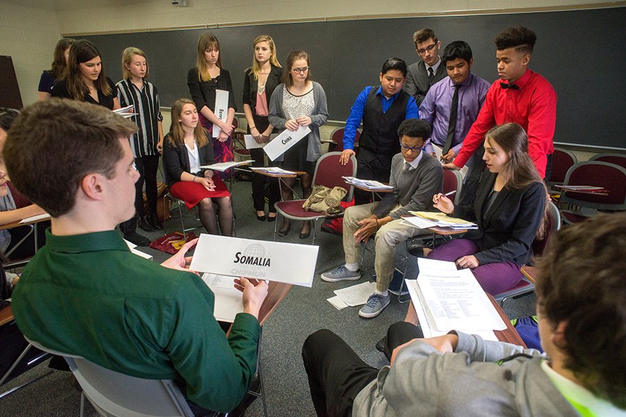 A large group of students gather in a classroom to discuss their club project