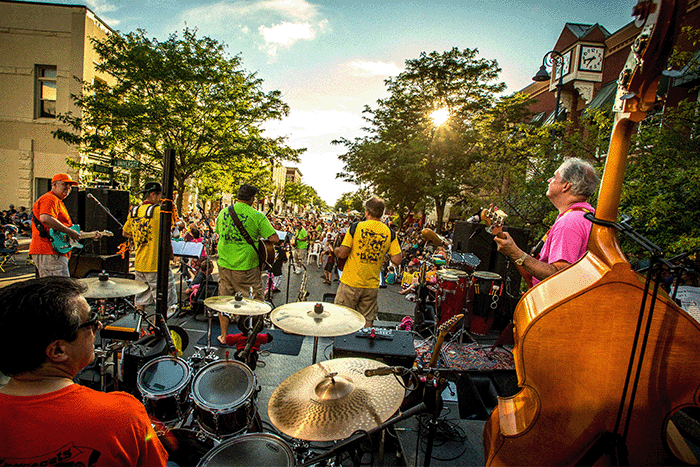 Five musicians ready their instruments for an outdoor concert in the street.